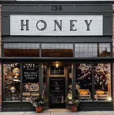 a store front with the words honey written on it's windows and potted plants outside