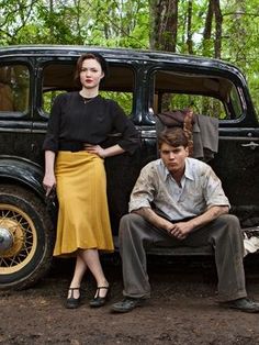 a man and woman sitting next to an old car