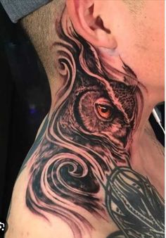 an owl tattoo on the side of a man's neck, with swirls