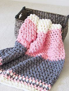 a crocheted blanket sitting next to a basket on the floor