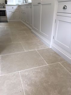 a kitchen with white cabinets and tile flooring