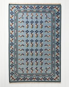 a blue rug with an arrow design on the front and back side, hanging from a white wall