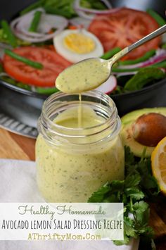 a spoon is pouring dressing into a jar filled with vegetables and sliced oranges on the side