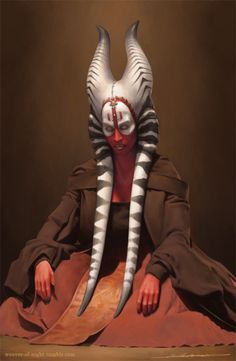 a man wearing a mask with horns on his head and sitting in front of a brown background