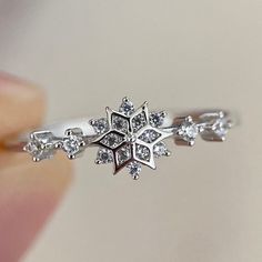 a close up of a person's hand holding a snowflake shaped ring