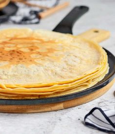 a stack of pancakes sitting on top of a pan with utensils in the background