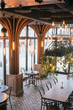 the inside of a restaurant with tables, chairs and plants in front of large windows