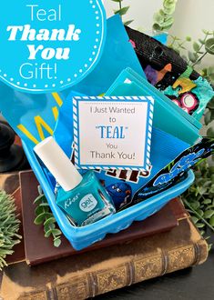 a thank you gift box with blue nail polish and other items in it on top of a book