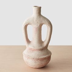 a white vase sitting on top of a wooden table