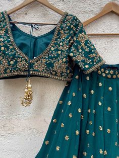 A three-piece green sharmily lehenga set from the Priti Sahni collection. This beautiful forest green georgette lehenga with sequin butti all over and zari scallop work border is paired with a green sequin, beads & zardozi hand-embroidered blouse. The lehenga has side hanging ball tassels to the waistline. And the blouse has a ghungroo tassel tie-up at the back. This outfit is completed with a nude sequined work net dupatta. Green Unstitched Georgette Choli, Embroidered Green Georgette Choli, Green Georgette Anarkali Set With Unstitched Blouse, Green Anarkali Set With Unstitched Blouse For Reception, Green Georgette Traditional Wear For Reception, Green Georgette Lehenga With Unstitched Blouse, Green Georgette Party Wear Sets, Green Georgette Choli For Festivals, Green Georgette Lehenga For Navratri