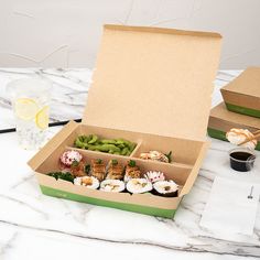 an open box filled with sushi and other food items on a marble counter top