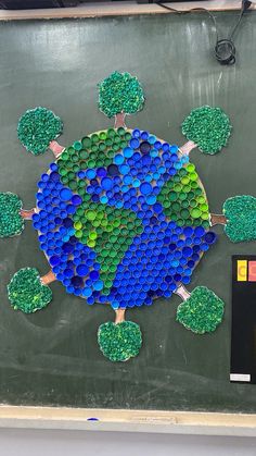 an art project made out of bottle caps on a blackboard with green and blue circles