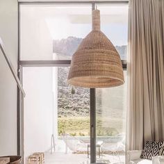 a living room with a large window and wicker lampshade hanging from the ceiling