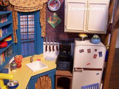 a doll house kitchen with blue cabinets and yellow counter tops, including a white refrigerator