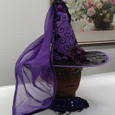 a purple hat on top of a mannequin's head in front of a painting