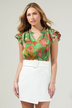 The Susy Paradise Bellissima Ruffle Sleeve Top will make you want another vacation with it’s tropical green and pink satin print. It has a highlighting silhouette followed by a split neckline and ruffle cap sleeves. The bodice maintains a classic fit that can easily be styled tucked into a pair of high waisted shorts and loafers for a classic look.- Cap sleeves- Split - Ruffle layers - Relaxed fit- Color: Green MultSize + Fit - Model is 5'8" and wearing size XS- Measurements taken from size S - Spring Satin Tops With Floral Print, Chic Green Blouse For Vacation, Fitted Green Blouse For Vacation, Green Tropical Print Blouse For Vacation, Green Floral Print Blouse For Brunch, Feminine Green Blouse For Vacation, Green Short Sleeve Blouse With Tropical Print, Green Tropical Blouse With Floral Print, Spring Satin Floral Print Tops