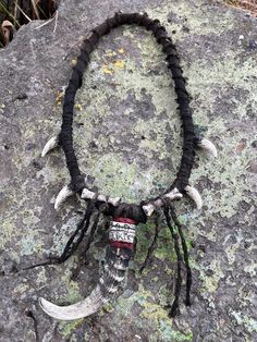 Step into the mystical world of shamanic rituals with our Shaman Necklace. This exquisite piece is crafted for those seeking to embrace their inner spiritual journey. Magnificently detailed and adorned with plastic goat horn and fake bones, this necklace is the perfect accessory for any shaman costume or fantasy-themed event. Ideal for horror lovers, LARP enthusiasts, or those attending ConQuest of Mythodea, this post-apocalyptic inspired jewelry exudes an aura of ancient wisdom and mysticism. G Spiritual Necklace For Halloween Festival, Spiritual Necklaces For Halloween Festival, Spiritual Halloween Festival Necklaces, Black Amulet Necklace For Festival, Ceremonial Amulet Necklace For Festivals, Shaman Necklace, Bone Necklace Native American, Apocalypse Costume, Shaman's Mask