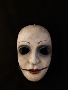 a white mask with black lines on it's face and nose, against a black background