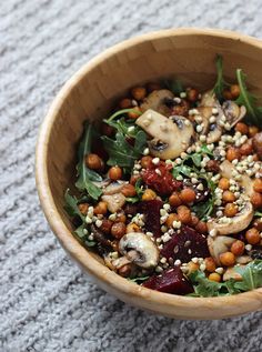 a wooden bowl filled with food on top of a carpet