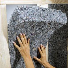 two hands reaching up on a rock with wood framing around it and another person's hand holding onto the rock