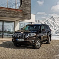 a brown toyota land cruiser parked in front of a building with mountains in the background