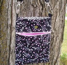 a black and white purse hanging on a tree trunk with pink ribbon around the strap