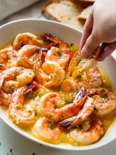 a person dipping some bread into a bowl of shrimp