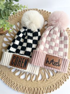 two hats with pom - poms sitting on top of a doily next to a potted plant