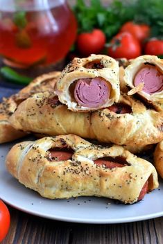 several sausage rolls on a plate with tomatoes in the background