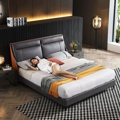 a woman laying on top of a black and white bed in a room with wood flooring