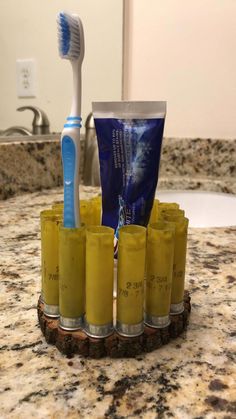 a toothbrush and some yellow cups on a marble counter with a sink in the background