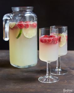 two glasses filled with lemonade punch and garnished with raspberries on the rim