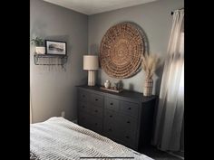 a bedroom with gray walls and white bedding, an african basket hanging on the wall