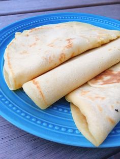 three quesadillas on a blue plate sitting on a wooden table