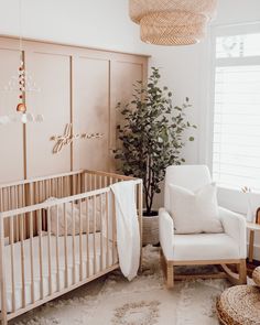 a baby's room with a crib, rocking chair and potted plant