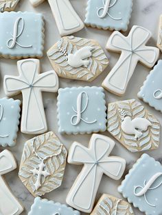 cookies decorated with white and blue icing are arranged on a marble countertop in the shape of crosses