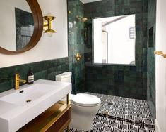 a green tiled bathroom with gold fixtures and black and white floor tiles on the walls