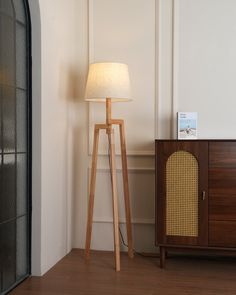 a floor lamp next to a wooden cabinet