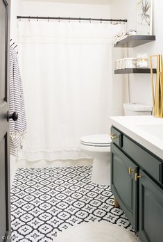 a bathroom with black and white tile flooring, gold accents on the shower curtain