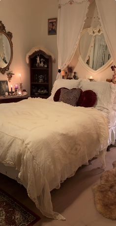 a bed with white sheets and pillows in a bedroom next to a mirror on the wall