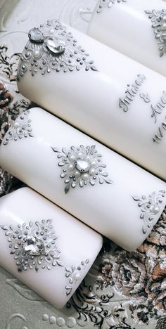 three white candles with silver decorations on them