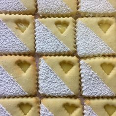 heart shaped pastries are arranged in rows on a white tablecloth with yellow and gray squares