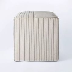 a white and grey striped ottoman sitting on top of a floor