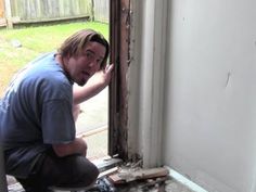 a man kneeling down next to a window in a room that has been gutted