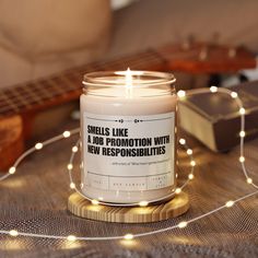 a candle that is sitting on a table with some string lights around it and a guitar in the background