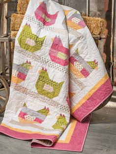 a quilted blanket sitting on top of a wooden chair next to hay bales