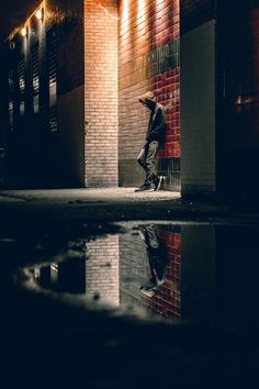 a man riding a skateboard down a street next to a tall brick building at night