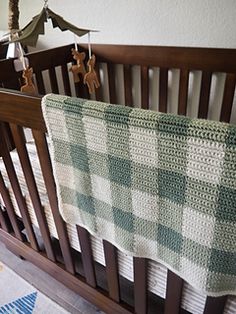 a crocheted baby blanket hanging from the side of a crib in a nursery