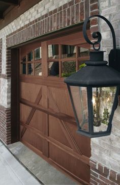 a garage door with a light attached to it and a brick building in the background