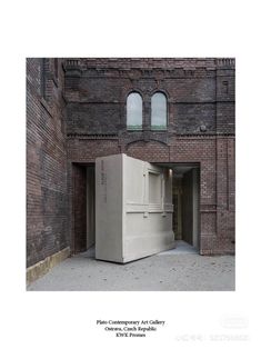 an old brick building with two windows and a large concrete box in the middle of it